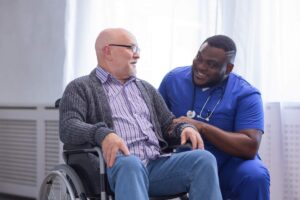 Family caregiver and home aide review a daily care plan with an older adult at a kitchen table.